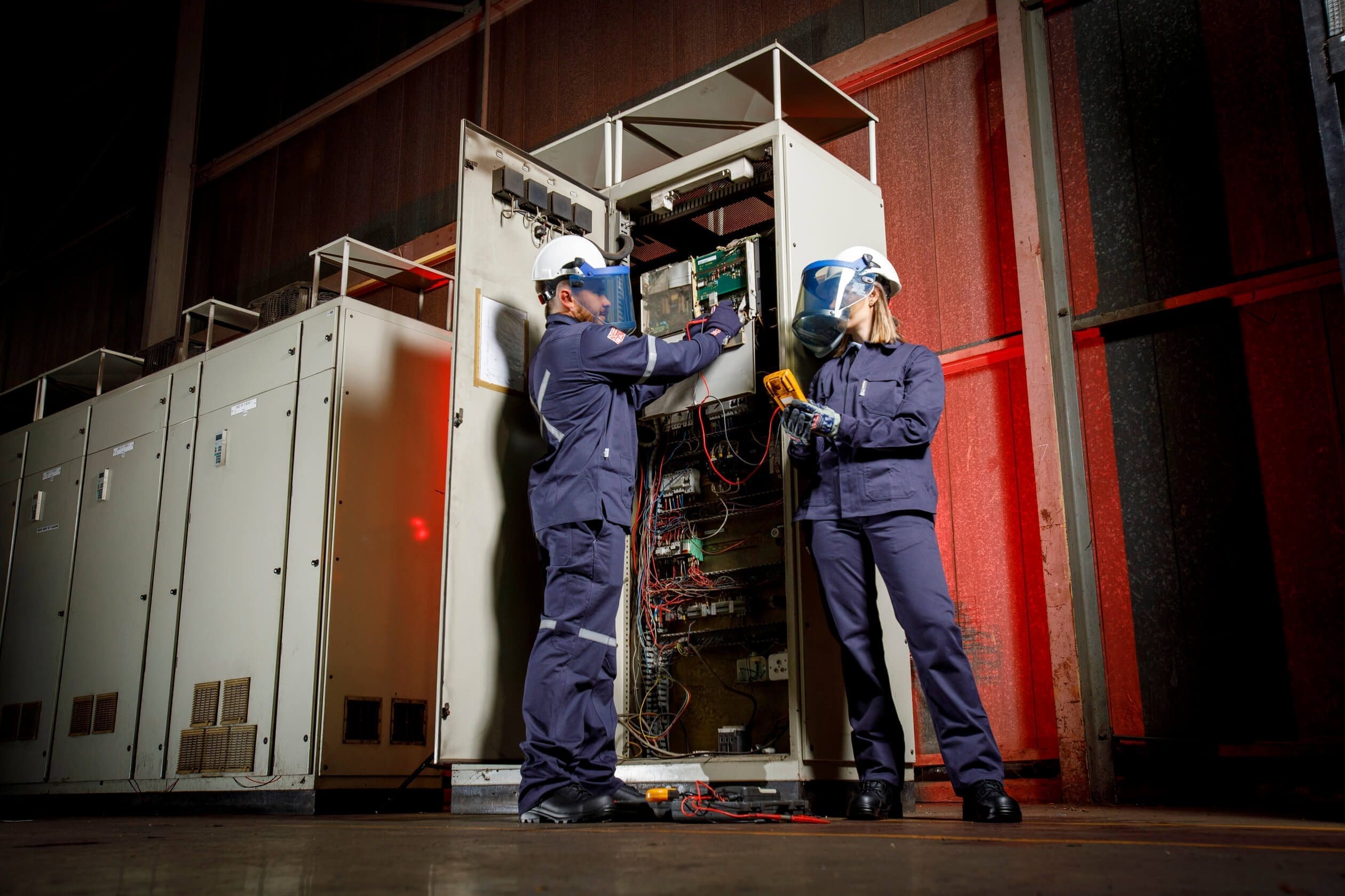 a man and woman wearing helmets and working on a machine